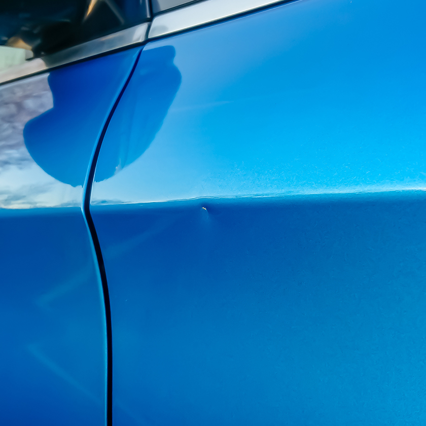 Dent in the door of a blue car